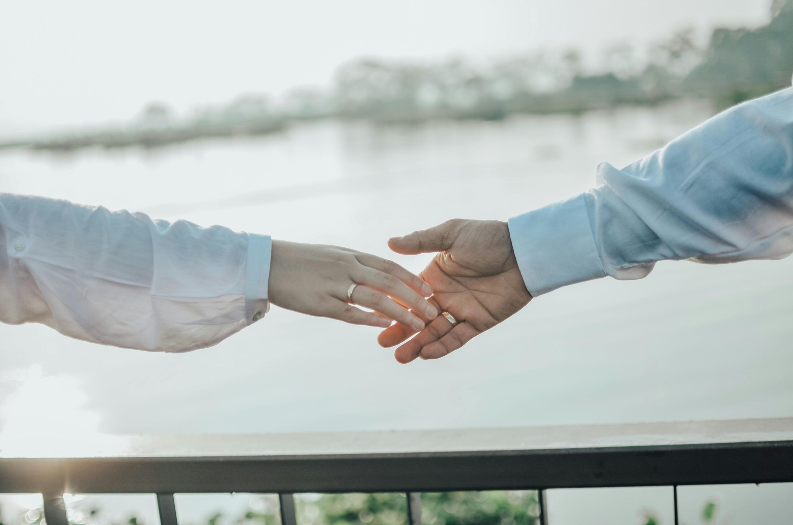 A couple gently reaching for each other's hands, symbolizing love and connection.