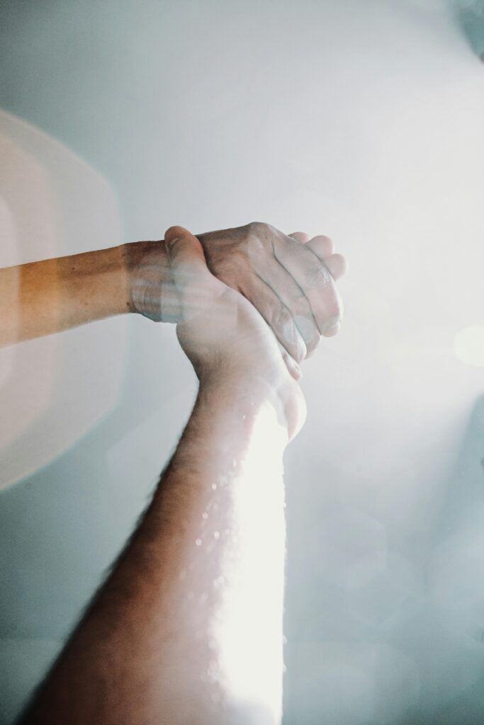 Two hands clasped, symbolizing unity and support with a bright, ethereal background.