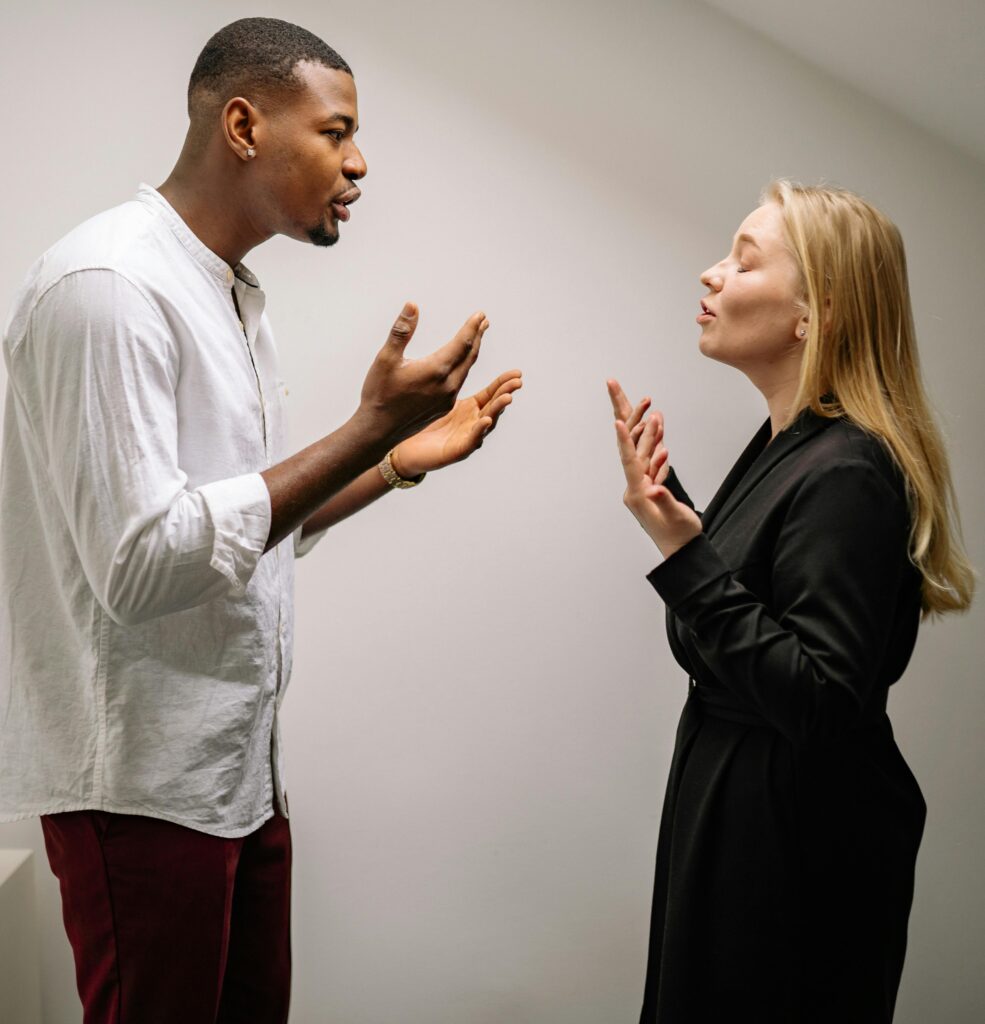 A couple engaged in a heated argument indoors, expressing strong emotions and gestures.