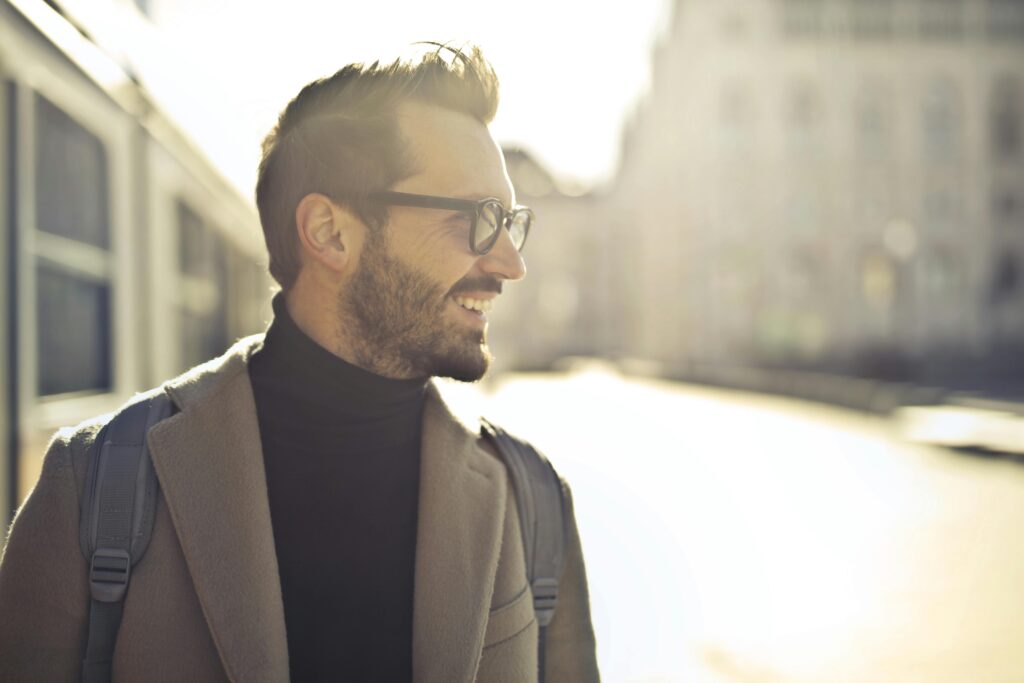 Smiling man with glasses and coat enjoying a sunny day in Budapest.