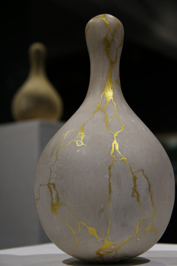 A close-up of an elegant ceramic vase featuring gold kintsugi on exhibit.