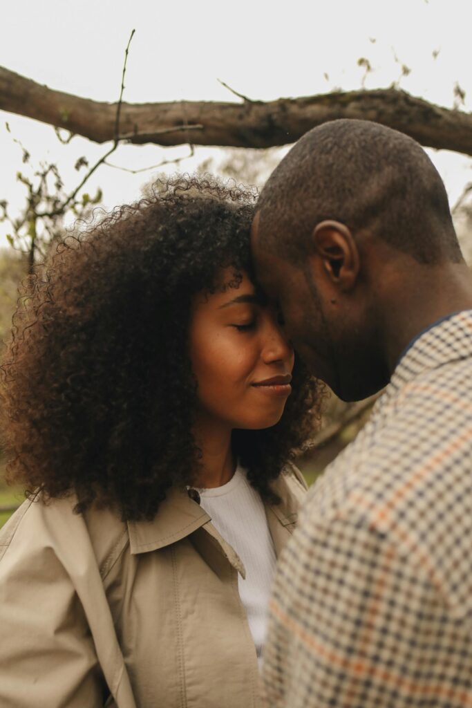 A close-up of a couple sharing a tender moment outdoors with foreheads touching.
